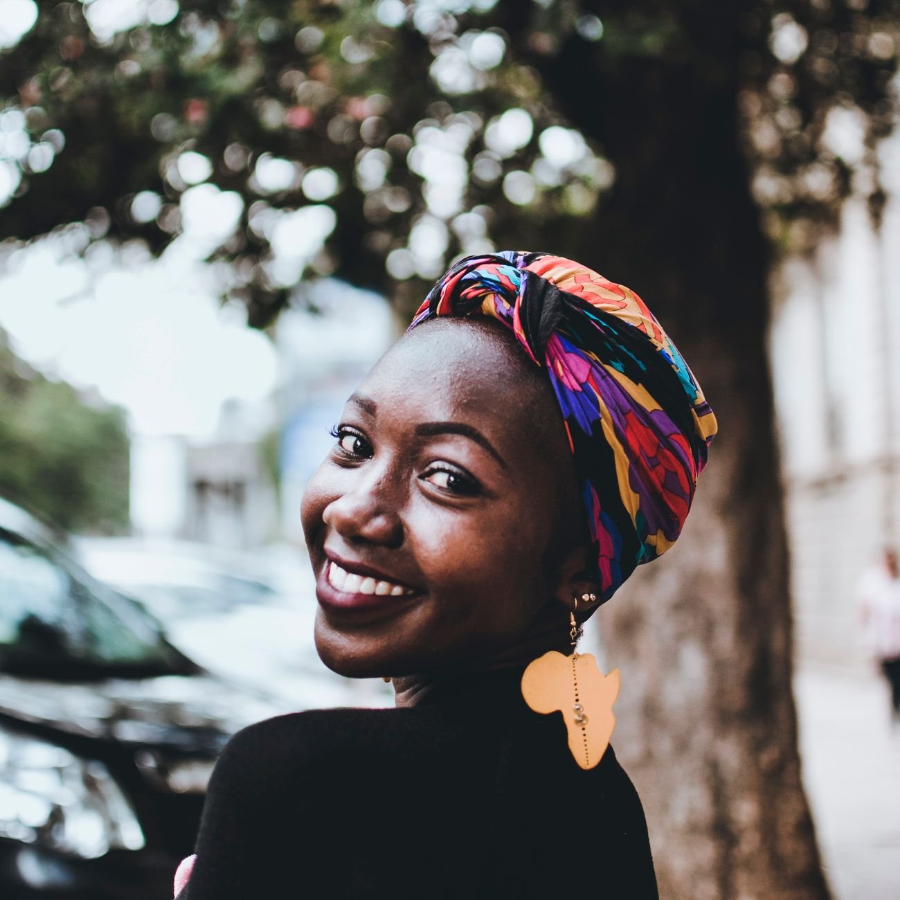 Smiling African woman in a vibrant headscarf, satisfied traveler